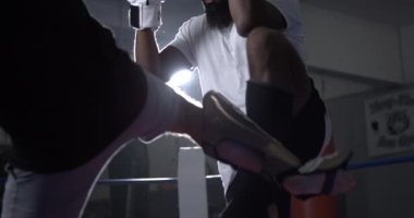 Muay Thai dövüşçüsü kendini boks ringinde rakip tekmeye karşı savunuyor. Dövüş sanatları eğitimi alan iki kişi.