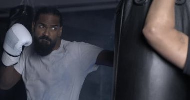 Odaklanmış boksör kum torbasına vuruyor boks eldivenlerini giyerek 800 fps hızla yüksek hızlı kamerayla yakalandı. Spor eğitimi.