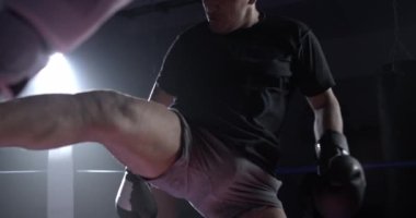 Yüksek hızlı kamerayla ağır çekimde yakalanan boks ringinde çarpıcı bir Muay Thai tekmesi. Dövüşçü rakibini tekmeliyor