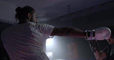 İki dövüşçü, boks ringinin içinde ağır çekimde birbirleriyle dövüşüyor. Rakip öğle yemeği, rakip bacağa tekme, rakibe vuruyor.