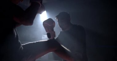 İki boks ringinde karşılaşan iki dövüşçü, ağır çekimde yakalanan rakipleri arasında gergin bir anda çarpışıyor.