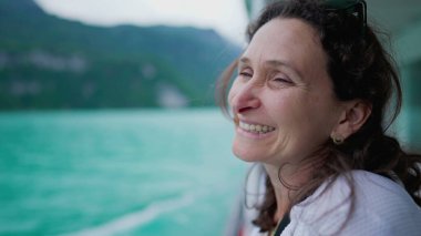 Mutlu kadın göl ve dağ manzarasını gözlemlemek için tekneyle seyahat ediyor, tatillerin tadını çıkarıyor, 40 'lı yaşlarda neşeli, dingin ve huzurlu bir kadın yüzü var.