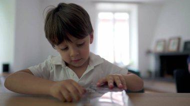 Küçük bir çocuk hediye kutusunu açıyor. Çocuk sabırsızlıkla doğum günü hediyesi alıyor. Çocuk oyuncak kutusunu yırtmaya çalışıyor.