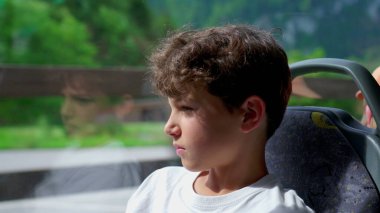 Otobüsteki yansıtıcı genç çocuk, uzak bakışlarda kaybolmuş. Genç gezgin koltuğa oturdu, derin derin düşündü ciddi bir ifade.