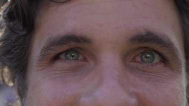 Makroyla gülümseyen bir adamın kameraya yakından bakan gözleri.