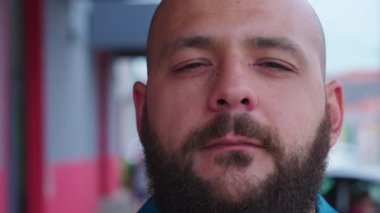 Şehirde kameraya bakan bir adamın yakın plan portresi.