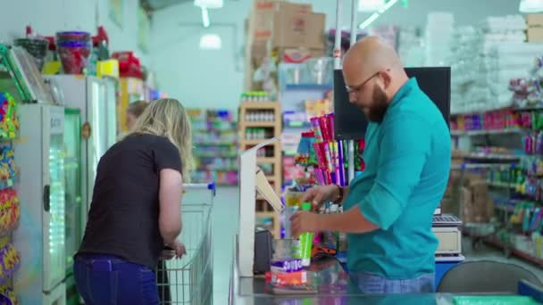 チェックアウト時にキャッシュスキャン製品の男性従業員 スーパーマーケットで商品を購入する女性顧客 — ストック動画