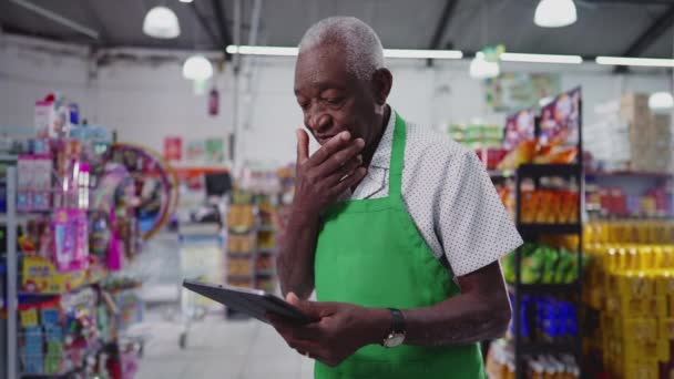 高级非洲男子围裙肖像 超级市场使用平板电脑 — 图库视频影像