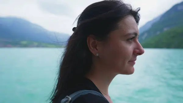 Peaceful woman traveling by boat staring at mountain and lake view , profile close-up contemplative face enjoying vacation travel