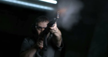 Adam 800 fp 'lik süper yavaş çekimde silahla nişan alıyor ve ateş ediyor. AK-47 Kalaşnikof Tüfeği taşıyan kişi, düşük açılı perspektif