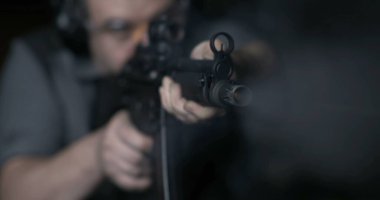 Ağır çekimde bir saldırı tüfeğini nişan alan ve ateşleyen bir adama yakın çekim, yüksek hızda 800 fps. Güçlü bir silahla ateş eden kişi.