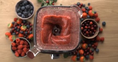 Meyve suyunu karıştırma ve hazırlama blenderin içinde süper yavaş çekimde üst perspektiften 800 fps ile antioksidan besin açısından zengin ahşap masa