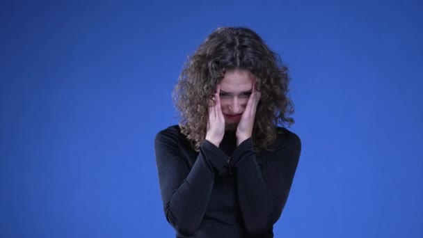 沮丧的女人对过去的回忆感到后悔和困惑 20多岁的女人满脸羞愧和焦虑地站在蓝色的背景上 — 图库视频影像