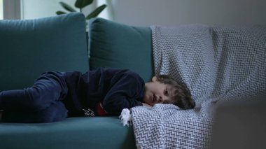 Küçük çocuk kanepede uzanmış kameradan çizgi film izliyordu. Çocuk eğlence içeriğiyle hipnotize edildi. Evde rahatladı.