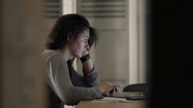 Evde, bilgisayarın önünde internette gezinen bir kadın. Gecenin geç saatlerinde bilgisayar ekranının önünde gerçek yüzünü gösteren gizli bir sahne.
