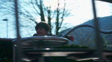 Küçük çocuk hoş bir şekilde döner döner döner döner döner, enerjik çocuk kaygısız bir şekilde eğlenir. Çocuk oyun sahasındaki atlıkarıncada neşeyle oynuyor.