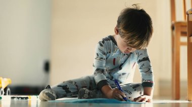 Sabah Yaratıcılığı - Pijamalı Çocuk Yerde Mavi Kalemle Çizim Yapıyor