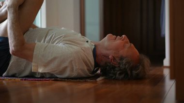 Sırtında bacak esneten yaşlı bir adam, yaşlılığında sağlığıyla ilgilenir. Emekli Kafkas Adam Sabah Bacağı Egzersizlerine Odaklanıyor