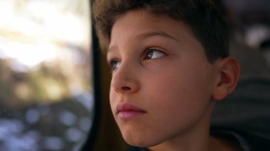 Tren gezisi sırasında düşünceli genç bir çocuk manzaranın yanından geçerken derin derin bakan ergen bir çocuğun yüzüne bakıyor.