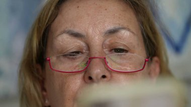 Gözlüklü, cep telefonu aygıtını tutan, içeriği tarayan ya da mesajları okuyan üst düzey kadın gözleri ve yüz okuma içeriği