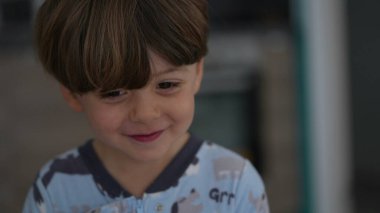 Heyecanlı küçük çocuk mutlu ve beklenti içinde. Sabahları pijama giyen mutlu çocuk portresi, coşkulu bir duygu.