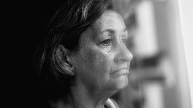 Endişeli, bunalımlı, son sınıf öğrencisi, kapanık, pencerenin kenarında duran ve iç karartıcı bir bakış açısıyla dışarı bakan bir kadın. Tek renkli siyah beyaz, endişeli duygu.