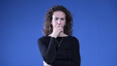 Düşünceli kadın, çenesini kapatıp derin derin düşünüyor sorunların çözümünü düşünüyor. Mavi arka plandaki düşünceli kişi