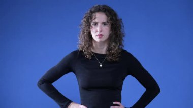 Üzgün kadın, kalça üstüne ellerini koyuyor. Endişe duyuyor ve haberlere inanmıyor. Kollarını kavuşturup olumsuz tepki veriyor.