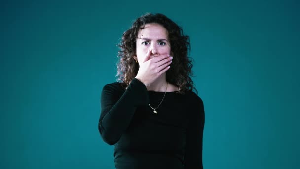 Överraskad Kvinna Täcker Munnen Med Handen Chockad Nyheter Teal Bakgrund — Stockvideo