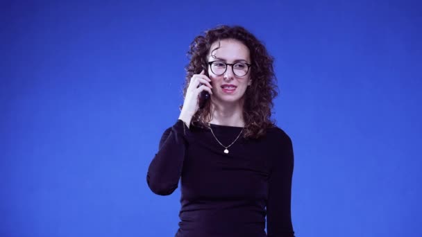 Γυναίκα Μιλάει Στο Τηλέφωνο Ενώ Στέκεται Μπλε Φόντο Μια 20Άρα — Αρχείο Βίντεο