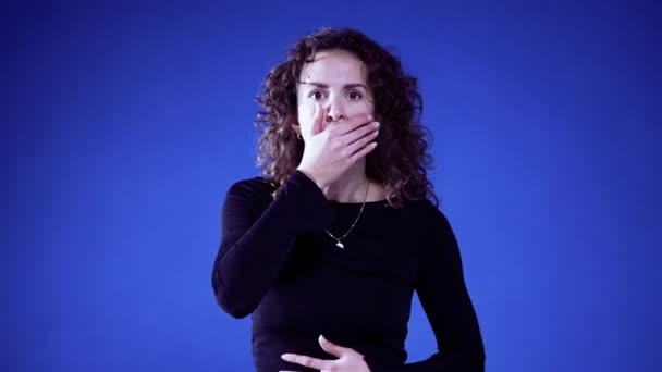 ブルーの背景にハンドオーバーマウスでショッキングニュースに反応する女性 彼女の目に不信感 — ストック動画
