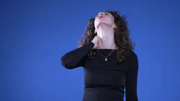 青い背景に立っている間 首の痛みに苦しんでいる女性 ストレスやプレッシャーによる硬い体を経験している方 — ストック動画