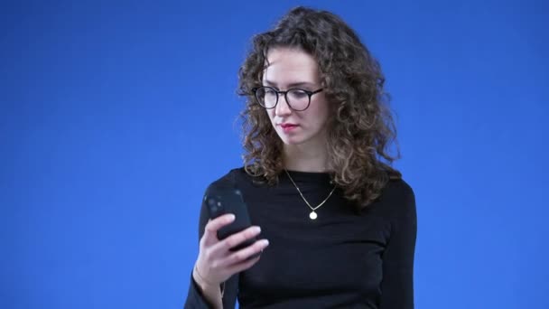 Frau Zieht Handy Empfangsbenachrichtigung Während Sie Auf Blauem Hintergrund Steht — Stockvideo