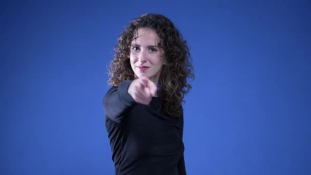 Kobieta Wskazująca Palcem Kamerę Sygnalizującą Gestem Ręki Stojącej Niebieskim Tle — Wideo stockowe