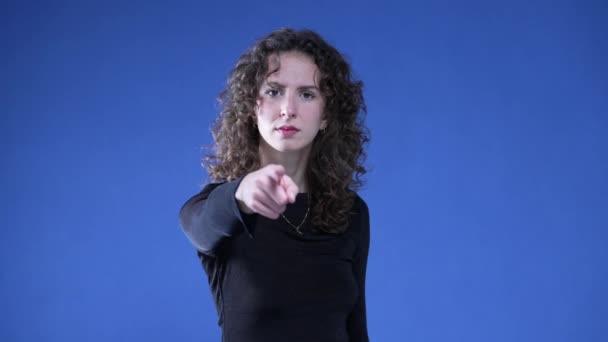 Γυναίκα Κατηγορώντας Θεατή Δάχτυλο Στην Κάμερα Ενώ Στέκεται Μπλε Φόντο — Αρχείο Βίντεο