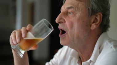 Son sınıf öğrencisi birasından bir yudum alıyor, kendinden büyük birinin alkollü içeceği içerken görüntüsünü yakından çekerken zihinsel yansıması, samimi ve otantik.