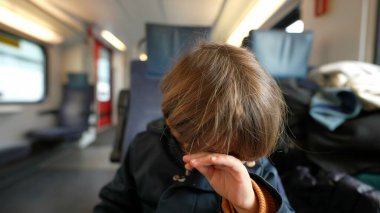 Trenle seyahat ederken el ile gözünü ovuşturan çocuk. Küçük çocuk kaşınıyor, kaşınıyor.