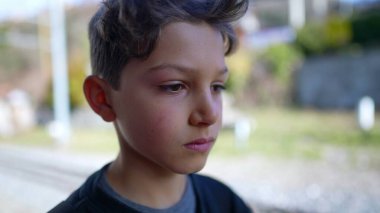 Ciddi bir genç çocuk. Kapalı kapılar ardında kameraya bakıyor.