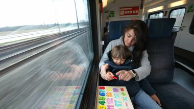 Dikkatli anne ve oğul, hızlı bir tren yolculuğunda eğitim egzersizlerinin tadını çıkarıyorlar.