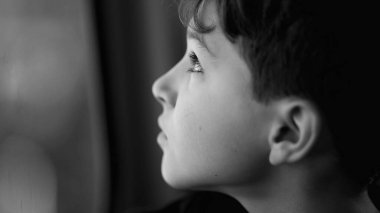 Depresyonda olan ergen bir erkek çocuk pencerenin önünde tefekkür ederek seyahat ediyor. Düşünceli çocuk profili yakın plan