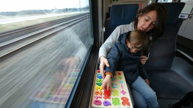 Dikkatli anne ve oğul, hızlı bir tren yolculuğunda eğitim egzersizlerinin tadını çıkarıyorlar.