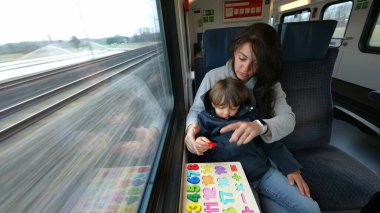 Dikkatli anne ve oğul, hızlı bir tren yolculuğunda eğitim egzersizlerinin tadını çıkarıyorlar.