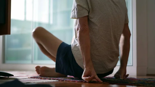 Senior man getting up from floor during morning exercise routine. elderly caucasian person sitting down in lotus position getting ready to meditate