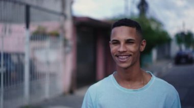 Kentli sokak ortamında kameraya doğru yürüyen mutlu, kendinden emin, genç bir Brezilyalı. Neşeli bir Güney Amerikalı portresi
