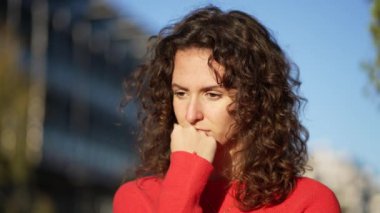 Düşünceli, çenesi havada bir kadın gün batımında derin derin düşünerek dışarıda duruyor. 20 'li yaşlarda kadın iç gözlemcilerin yakın çekimi.