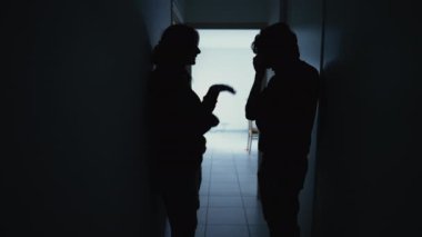 Silhouette of couple standing in corridor in crisis. Parents with child feeling worry and anxiety. Husband and wife discussing difficult situation