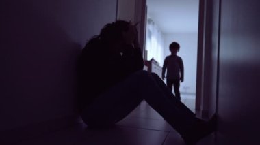 Child hugging mother suffering at home floor. Little boy silhouette consoling parent during depression. Single mother with kid