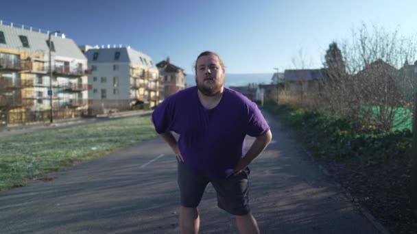 屋外で運動する前に体を伸ばすプラスサイズの男性 ランニングのために準備する体の前向きに外に立っているカジュアルな男性 — ストック動画