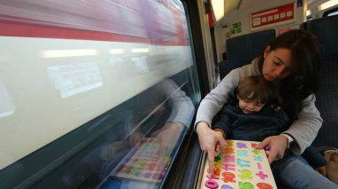 Proaktif bir anne, hızlı tren yolculuğu sırasında oğluna eğitim faaliyetlerini kolaylaştırıyor. Hareket hâlindeki çocukluk eğitimini örnek alıyor.