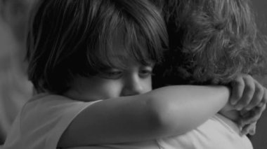 Düşünceli küçük çocuk aile üyesine sarılıyor. Üzgün ve melankolik olduğunu belirten, kollarıyla düşünceli bir çocuk.